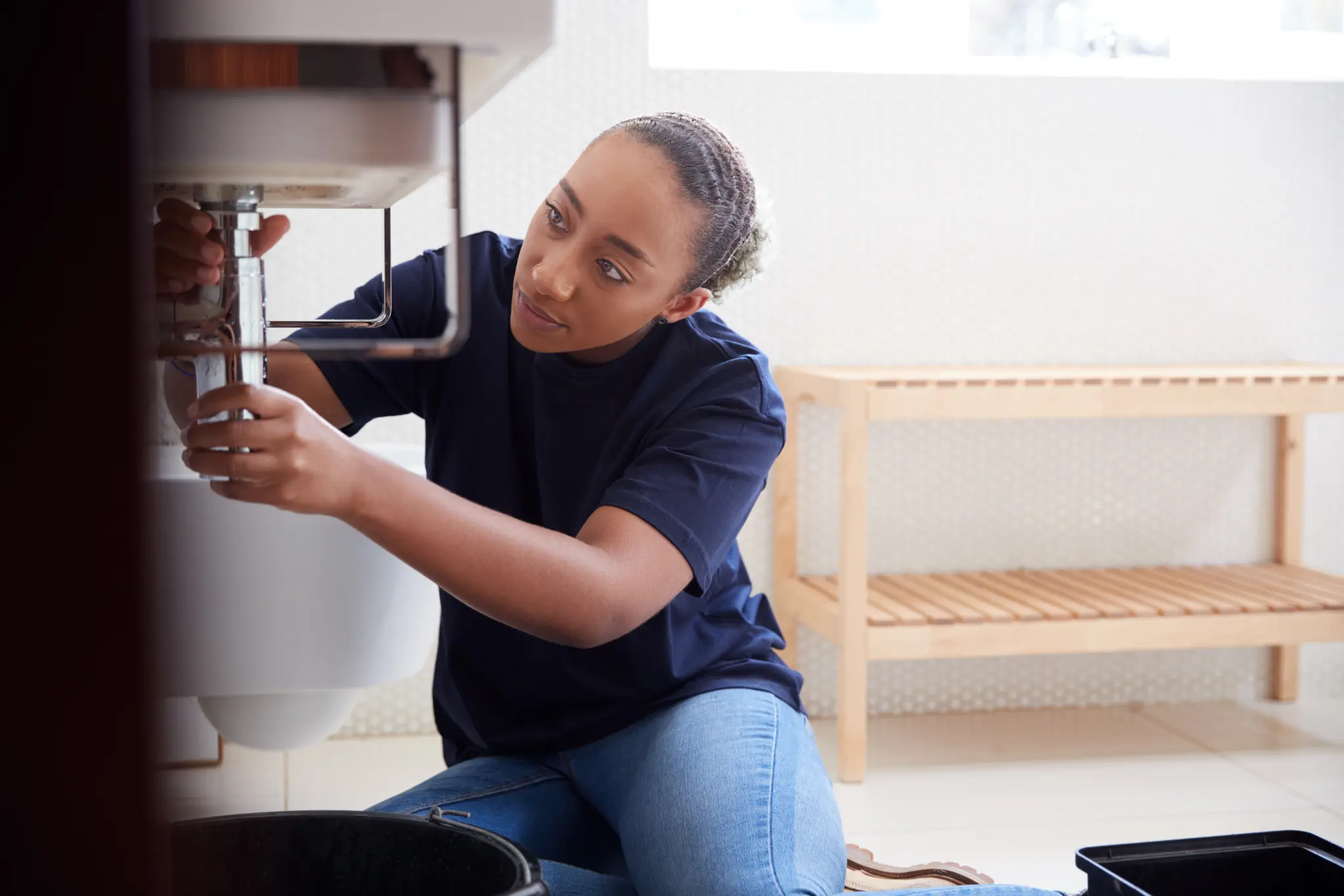 Plumber repairing the chrome drain pipe connections beneath a sink