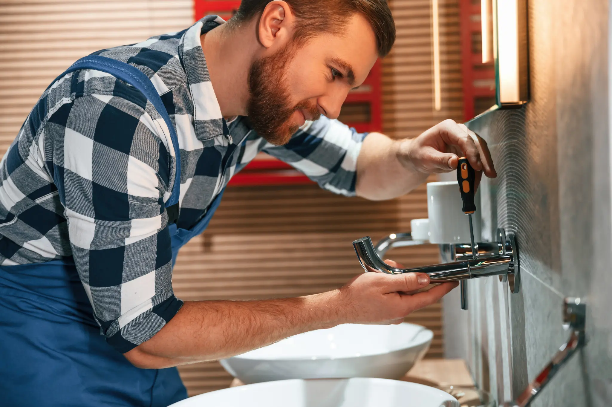 Plumber using a screwdriver to repair a residential bathroom fixture